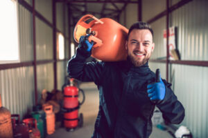 Happy Worker In Liquified Gas Storage With Cylinder On His Back