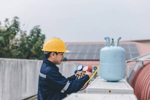 Technician is checking air conditioner. Air conditioning, HVAC service technician using gauges to check refrigerant and add refrigerant.